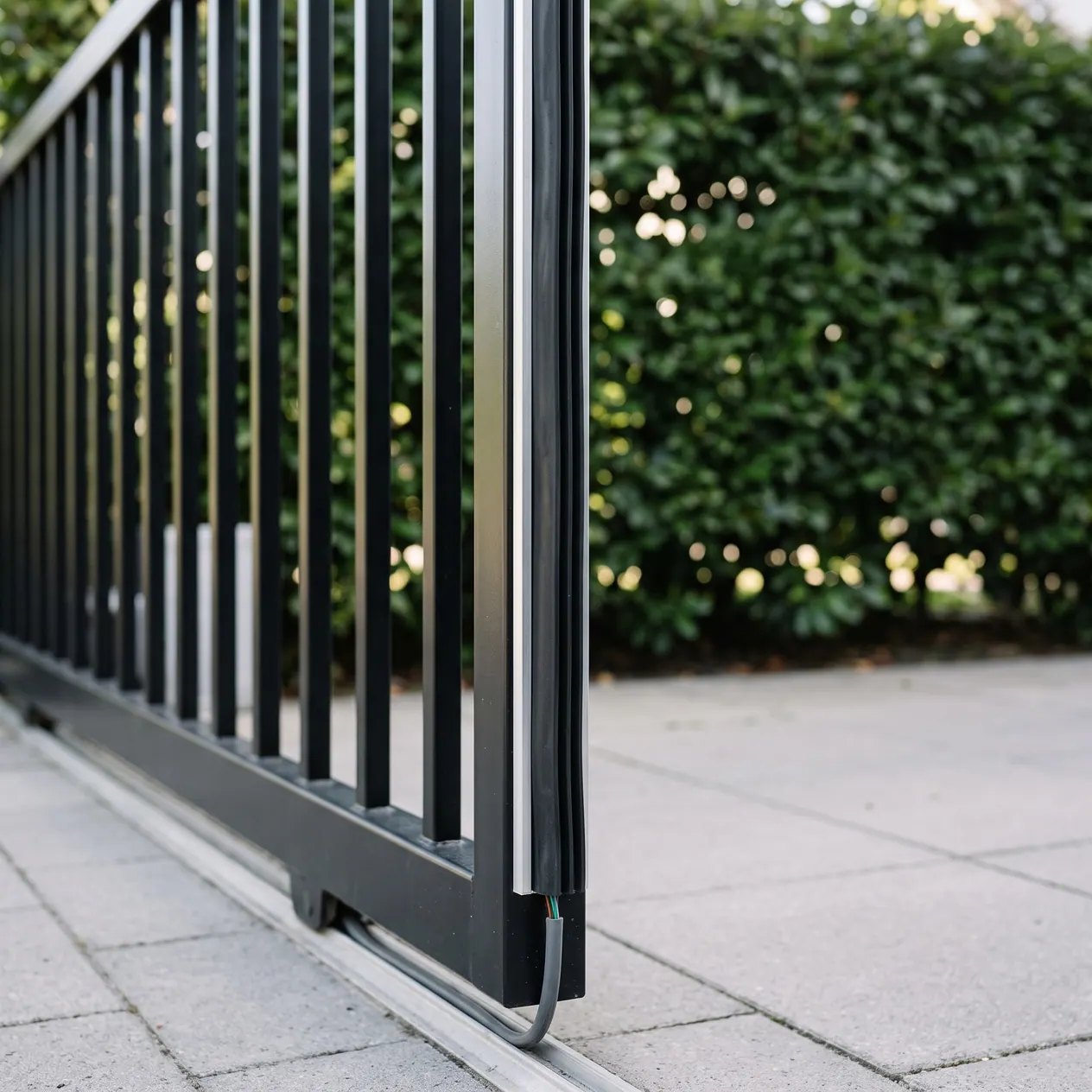 A black rubber safety edge running down the leading end of a steel slide gate